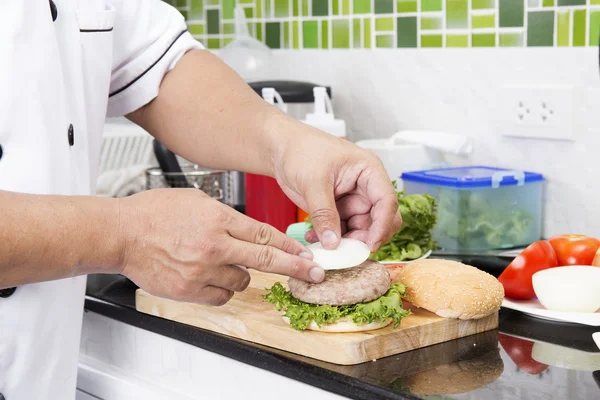 Chef poniendo hamburguesa de cebolla en el pan — Foto de Stock