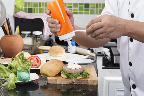 Chef putting mayonnaise on the Hamburger bun — Stock Photo, Image