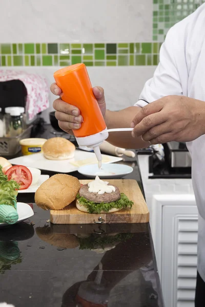 Chef colocando maionese no pão de hambúrguer — Fotografia de Stock