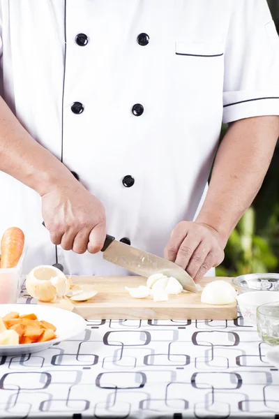 Chef coupant l'oignon sur une planche de bois — Photo