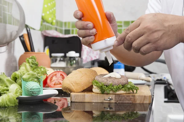 Chef poniendo mayonesa en el pan de hamburguesa — Foto de Stock