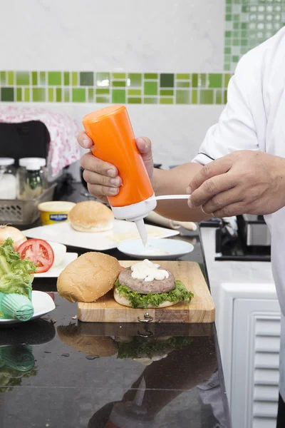 Chef putting mayonnaise on the Hamburger bun — Stock Photo, Image