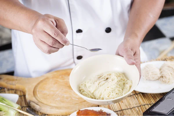 Koch kocht Nudeln mit Gewürzsoße — Stockfoto