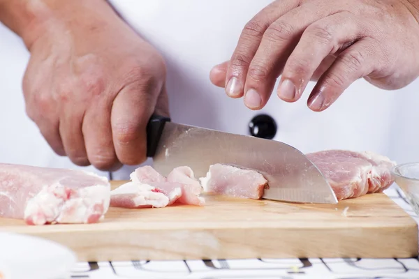 Šéfkuchař řezání syrového vepřového na dřevěné desce — Stock fotografie