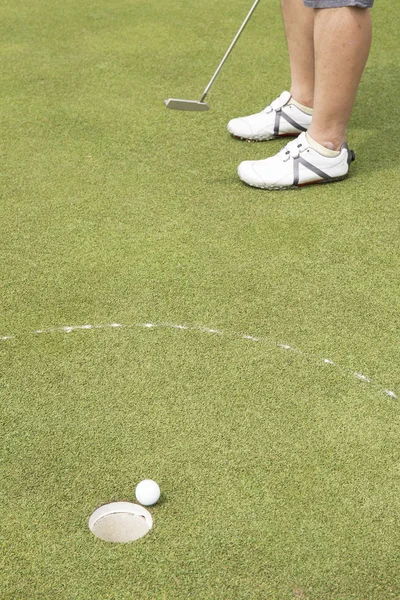 Jugador de golf poniendo pelota en el agujero — Foto de Stock