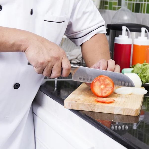 Kockens händer skära tomat — Stockfoto