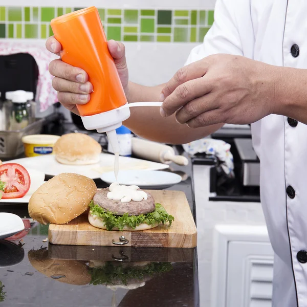 Chef putting mayonnaise on the Hamburger bun — Stock Photo, Image