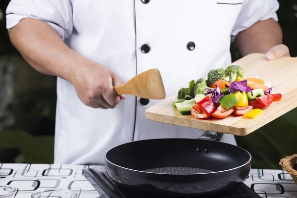Шеф-кухар кладе овочі на сковороду — стокове фото
