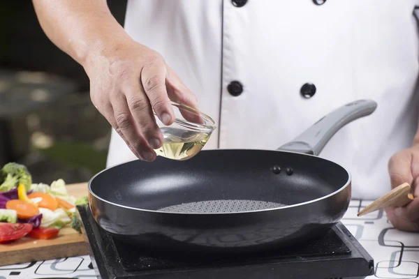 Chef pouring vegetable oil to the pan — Stock Photo, Image