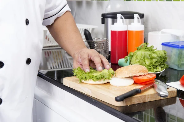 Chef poniendo lechuga en el pan — Foto de Stock