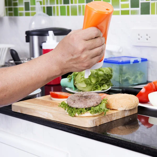 Chef putting mayonnaise on the Hamburger bun — Stock Photo, Image