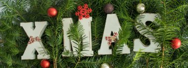 Ağaç dalları, kırmızı dekoratif toplar ve yıldızlı Noel afişi. Düz yatıyordu