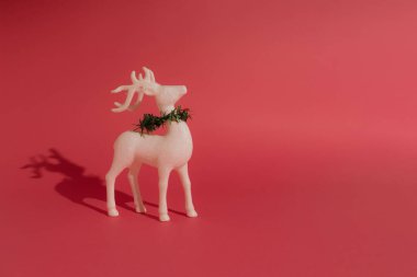 Pastel gül arka planında yeşil Noel çelengi olan beyaz ren geyiği. Yeni Yıl Minimum Konsepti