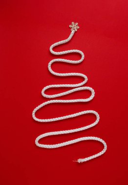 Kırmızı arka planda beyaz ipten yapılmış bir Noel ağacı. Asgari yeni yıl konsepti. Düz yatıyordu.