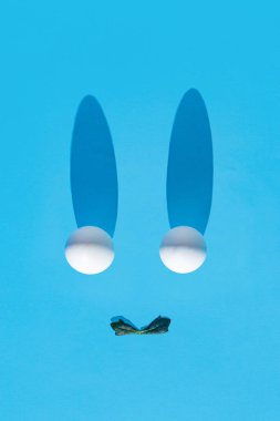 Paskalya 2021, açık mavi arka planda beyaz yumurta ve yeşil yapraklı yaratıcı kompozisyon. Minimum bahar tatili konsepti. Düz yatıyordu.