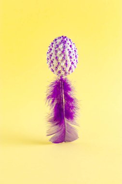 Mor etiketli doğal yumurtaların yaratıcı Paskalya konsepti sarı arka planda mor bir yüzgecin üzerinde duruyor. Asgari tatil veya bahar konsepti.