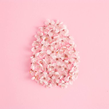 Bahar çiçekleri ve gül arkaplanlı yaratıcı Paskalya yumurtası kompozisyonu. Doğal koncept. Düz yatıyordu.