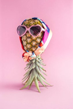 Güneş gözlüklü, eşarplı, şık meyveli Pineapple hipster ile yaratıcı bir yaz fikri. Minimum tropikal konsept. Sanat modasına uygun tatil konsepti. Yaz mevsimi renk havası, ananas meyvesi