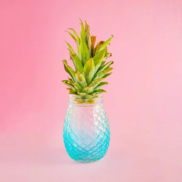 Summer composition with green pineapple leaves and a glass bottle. Minimal creative food concept.