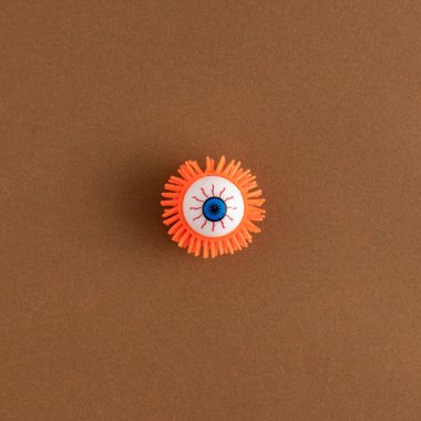 Kahverengi arka planda yaratıcı renkli cadılar bayramı kanlı gözü. Ürkütücü bir kavram. Düz yatıyordu.