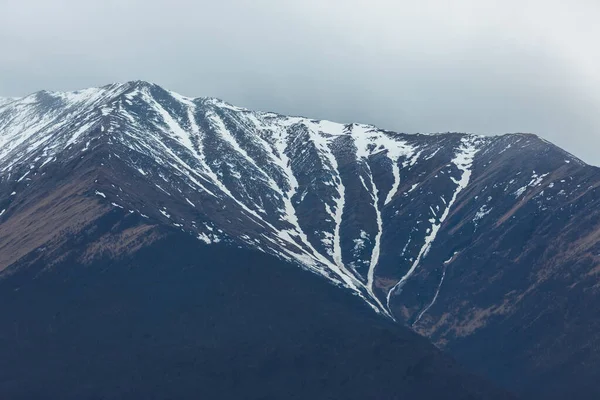 Заснеженные вершины и темные скалы — стоковое фото