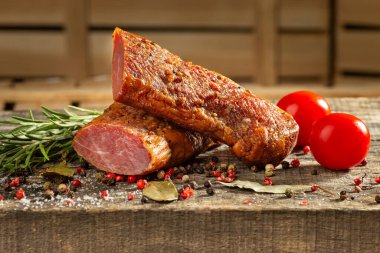 Smoked meat, Sliced smoked beef on a wooden table with addition of fresh herbs and aromatic spices.