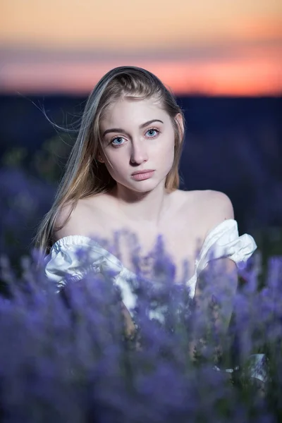 Beautiful blonde woman in the lavender field on sunset. Soft focus