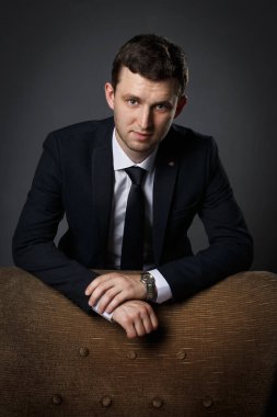 Siyah takım elbiseli, beyaz gömlekli ve siyah kravatlı bir iş adamı portresi.