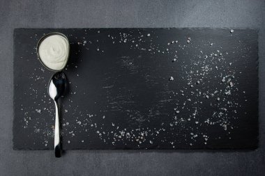 Deniz tuzu, kaşık ve kayıkla siyah taştan bir tahta. Karanlık bir arka planda. Üst Manzara. Boş alan.