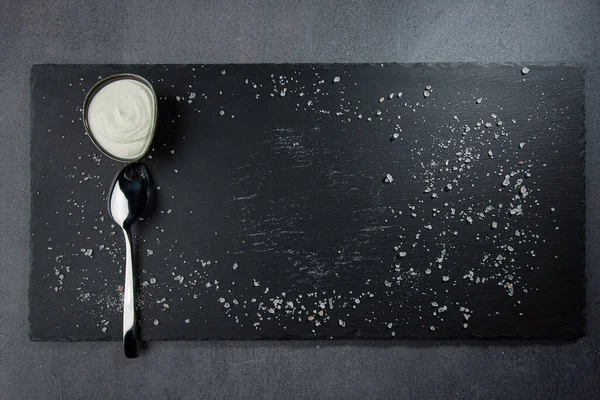 Deniz tuzu, kaşık ve kayıkla siyah taştan bir tahta. Karanlık bir arka planda. Üst Manzara. Boş alan.