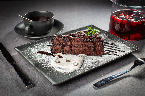 A piece of chocolate cake with mint on the table, close-up, served with fruit tea
