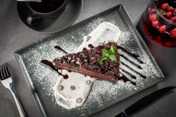 A piece of chocolate cake with mint on the table, served with fruit tea — Stockfoto