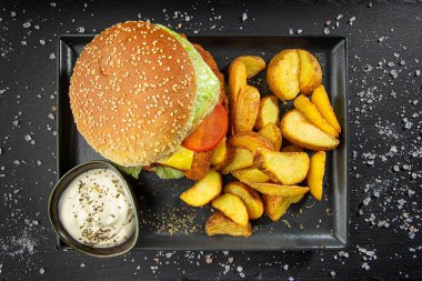 El yapımı burger ve patates kızartması, siyah arka planda izole edilmiş ekşi krema sosu. Fast food