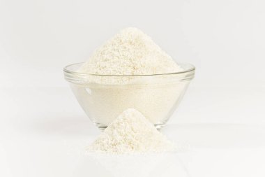 Cam bir kasede yere saçılmış hindistan cevizi taneleri, beyaz arka planda izole edilmiş hindistan cevizi.