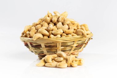 Hasır bir kasede kaju fıstığı. Beyazda izole edilmiş.