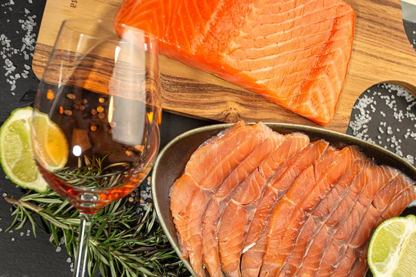 Glass of wine and smoked salmon sliced and in piece on a wooden board. Christmas and New Year background
