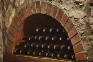 Şarap mahzeninde toz ve örümcek ağlarıyla kaplı eski şarap şişeleri.