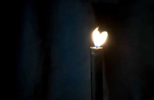 Heart shaped candle light. Candle fire in a dark room.