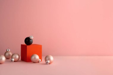 Kırmızı küpteki siyah Noel topu altın toplarla birlikte.