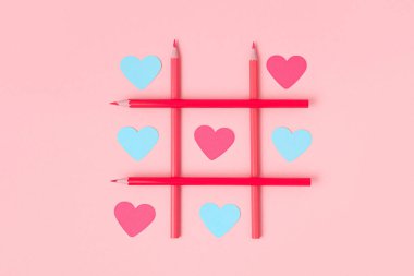 Pembe arka planda kağıt kesiği kalpler olan Tic-tac-toe