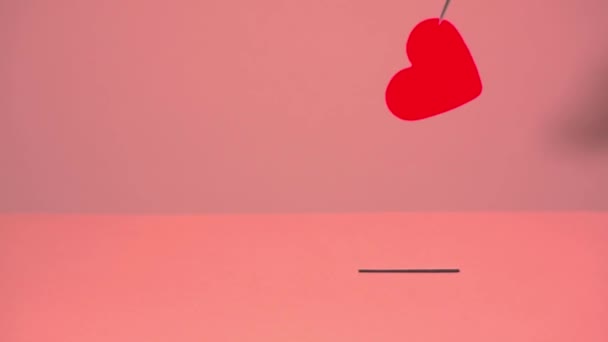 A red heart made of paper is held with tweezers and put in the slot — Stock Video