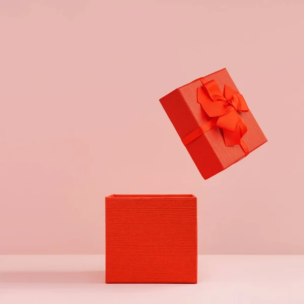 Red gift box with open lid on pink background