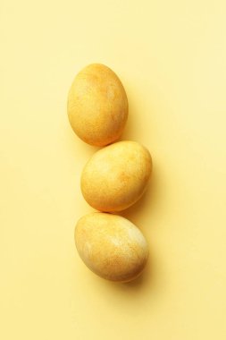 Sarı arka planda üç Paskalya altın yumurtası