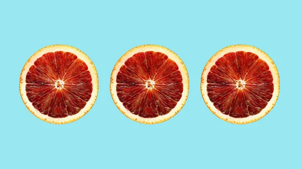 Three halves of a red orange in a row on a blue background