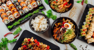 Masada geleneksel Asya yemekleri, deniz ürünleri ve suşi ile yüksek açılı tabaklar var.