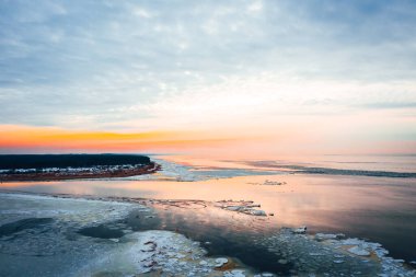 Donmuş deniz suyundaki hava manzarası güzel bir günbatımında mavi gökyüzüne karşı, kışın deniz kenarında. 