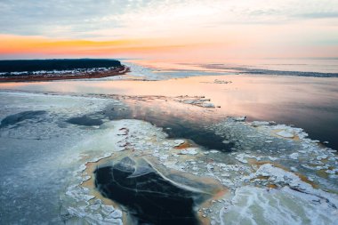 Donmuş deniz suyundaki hava manzarası güzel bir günbatımında mavi gökyüzüne karşı, kışın deniz kenarında. 