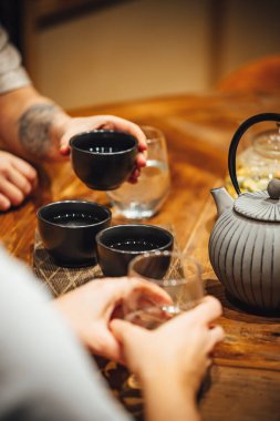 Tahta bir masada sıcak çay içen insanların seçmeli odak noktası. 