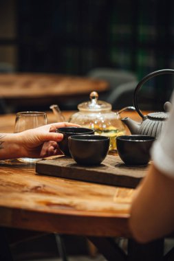 Tahta bir masada sıcak çay içen insanların seçmeli odak noktası. 