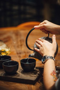 Tahta bir masada sıcak çay içen insanların seçmeli odak noktası. 